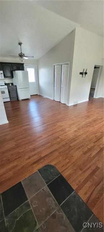 206 Oak St, Fulton, NY 13069 - unfurnished living room featuring baseboards, dark wood-style flooring, ceiling fan, and vaulted ceiling