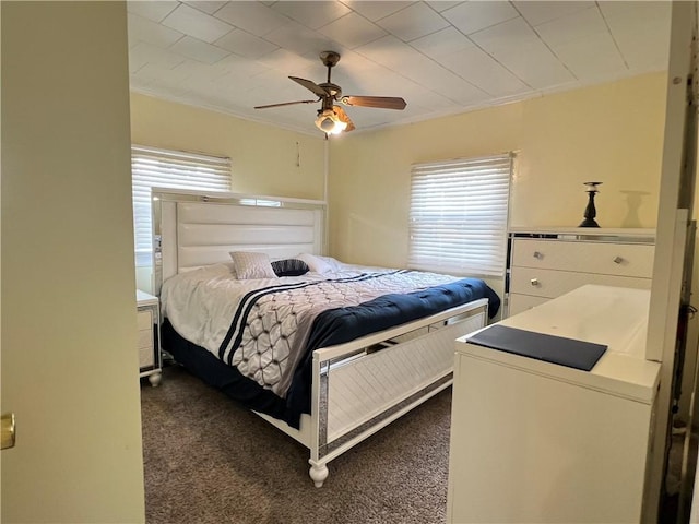 bedroom featuring dark carpet, ornamental molding, ceiling fan, and multiple windows