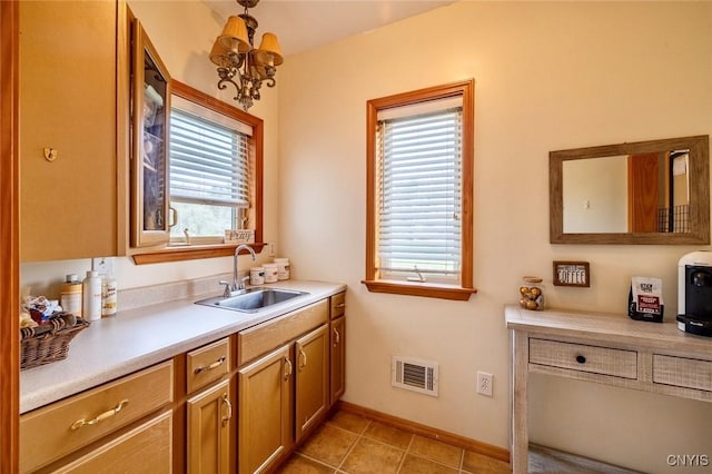 kitchen featuring a sink, light countertops, a chandelier, baseboards, and visible vents