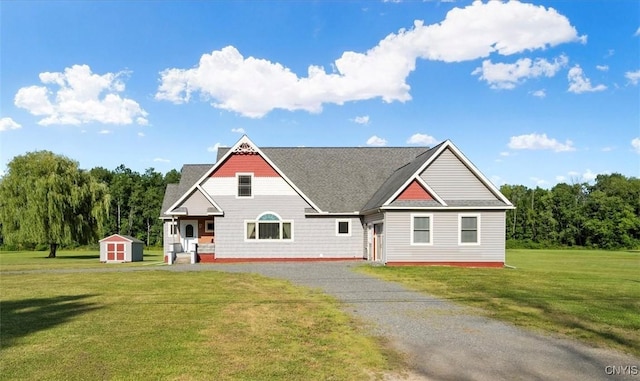 craftsman house with driveway, an outbuilding, a front yard, and a storage unit