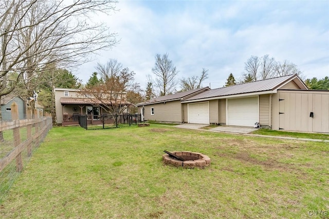 view of yard featuring fence, a fire pit, and an outbuilding