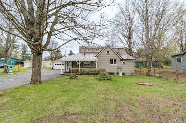 view of front facade with a porch, metal roof, a front yard, and aphalt driveway