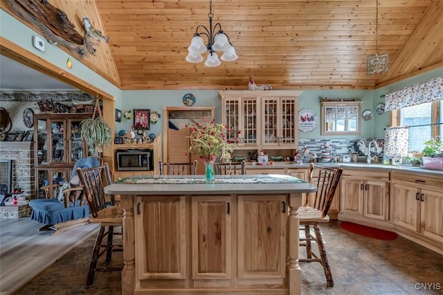 kitchen featuring stainless steel microwave, vaulted ceiling, a breakfast bar, and a center island