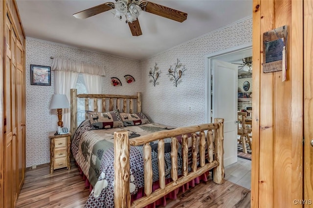 bedroom with crown molding, a ceiling fan, wallpapered walls, and wood finished floors