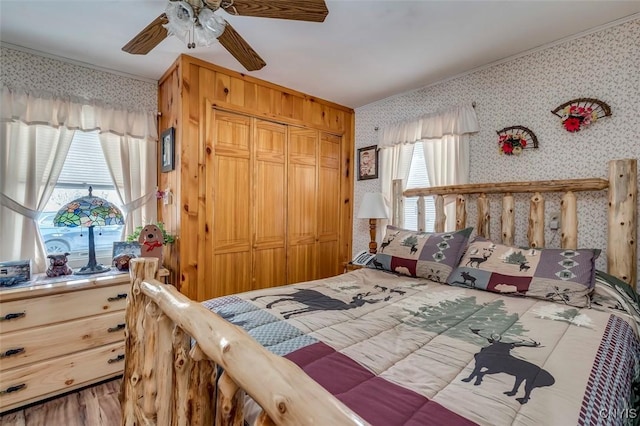 bedroom with a closet, a ceiling fan, ornamental molding, and wallpapered walls