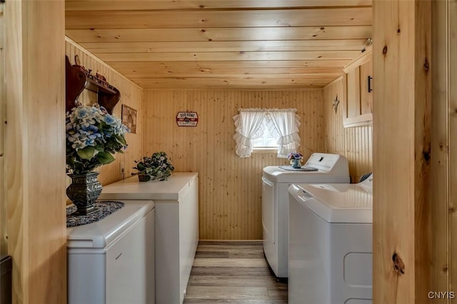 laundry area with light wood-style flooring, independent washer and dryer, wooden walls, and wood ceiling