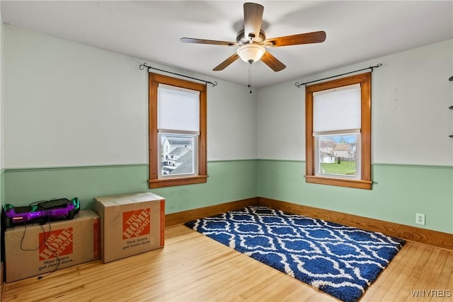 empty room with baseboards, a ceiling fan, and wood finished floors