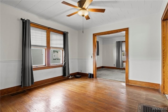 spare room with baseboards, ceiling fan, wood finished floors, and visible vents