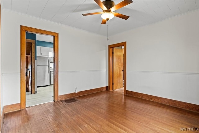 unfurnished room with visible vents, a ceiling fan, hardwood / wood-style floors, and ornamental molding