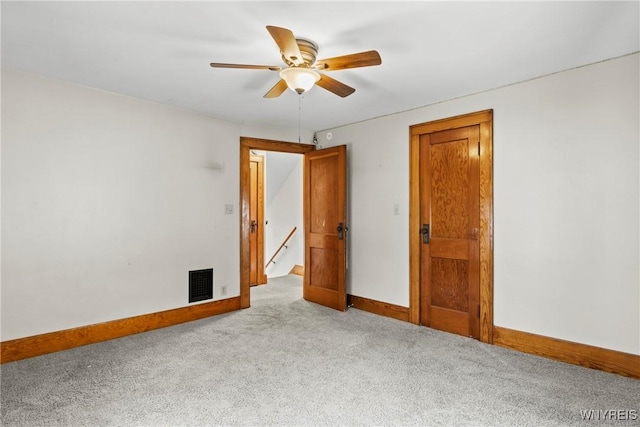 carpeted spare room with baseboards, a ceiling fan, and visible vents