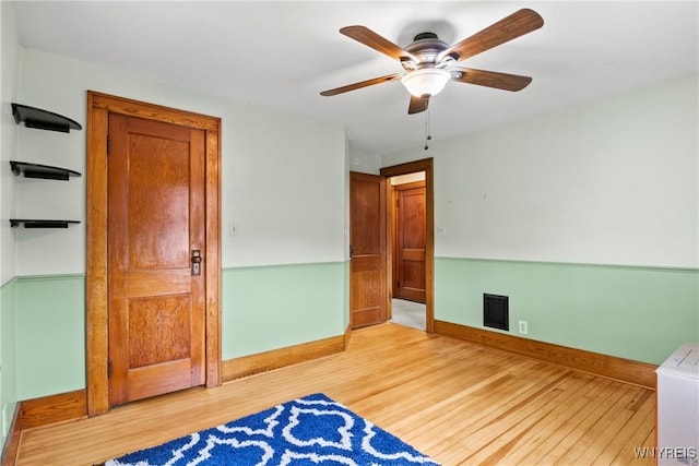 unfurnished bedroom with light wood-type flooring, a ceiling fan, baseboards, and visible vents