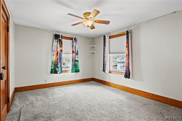 carpeted empty room featuring baseboards and a ceiling fan