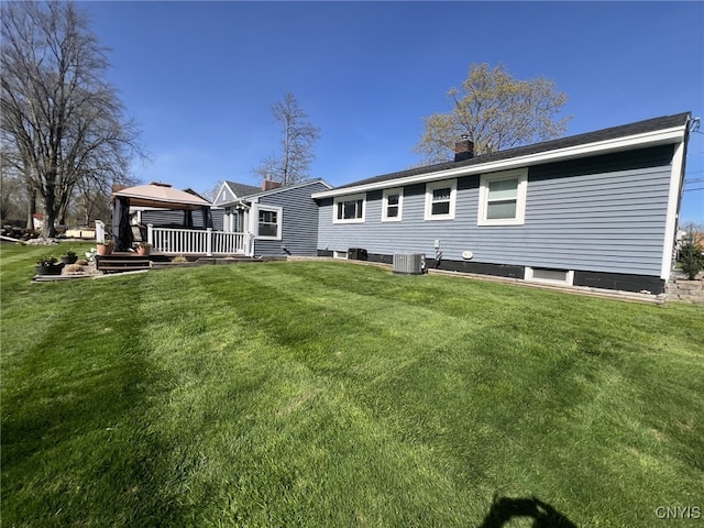 back of house with a chimney, a deck, central AC unit, a gazebo, and a yard