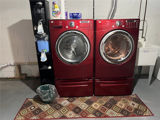 washroom featuring concrete block wall, laundry area, a sink, and washing machine and clothes dryer