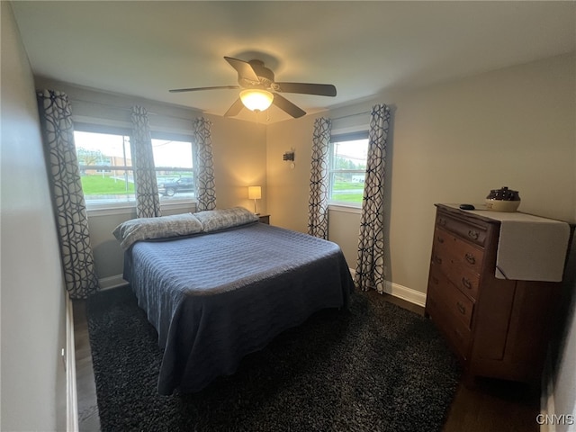 bedroom with dark wood-style flooring, a ceiling fan, and baseboards
