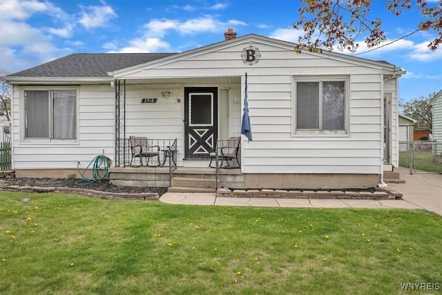 view of front facade featuring a porch, a front lawn, and fence