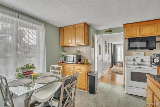 kitchen featuring black microwave, white range with electric cooktop, a textured ceiling, stainless steel microwave, and tasteful backsplash