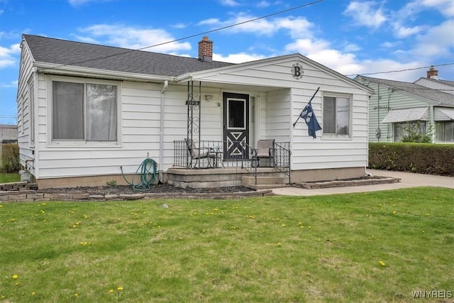 bungalow-style home with roof with shingles, a chimney, and a front yard