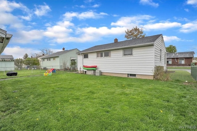 back of house featuring a yard, a chimney, and a fenced backyard
