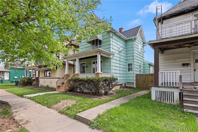 view of front of property featuring covered porch, fence, and a front lawn