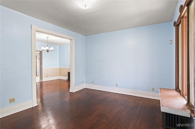 unfurnished room with baseboards, dark wood finished floors, and a notable chandelier