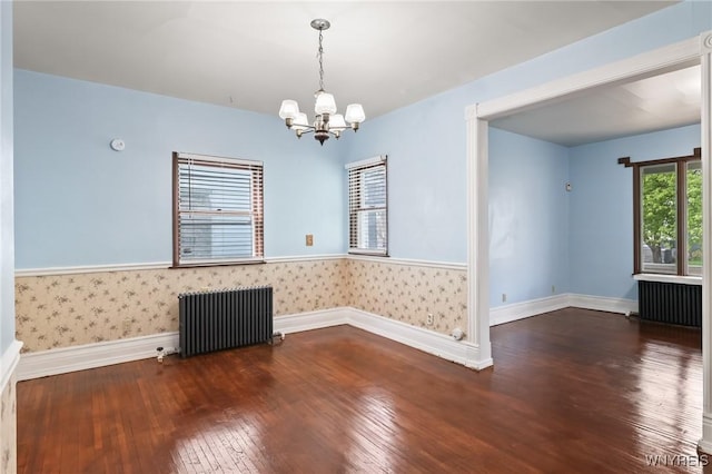 unfurnished room featuring baseboards, radiator, a notable chandelier, and hardwood / wood-style flooring