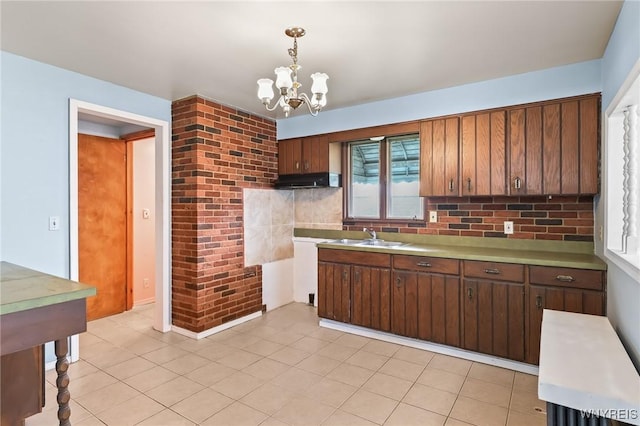 kitchen featuring pendant lighting, tasteful backsplash, light countertops, a notable chandelier, and under cabinet range hood