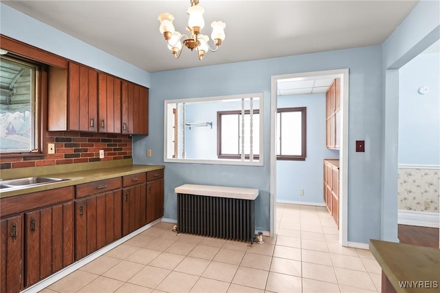 kitchen featuring a sink, light countertops, a chandelier, radiator heating unit, and baseboards