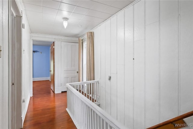 hallway with baseboards, dark wood-style floors, and an upstairs landing