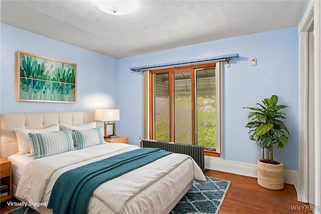 bedroom featuring radiator heating unit, baseboards, and wood finished floors