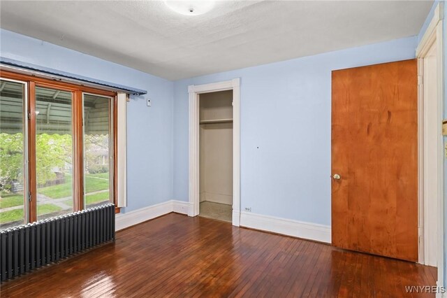 unfurnished bedroom with baseboards and hardwood / wood-style flooring