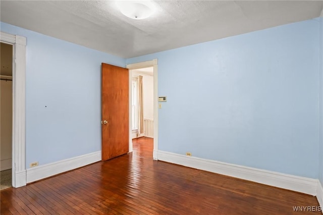 unfurnished bedroom featuring baseboards, a closet, and hardwood / wood-style floors