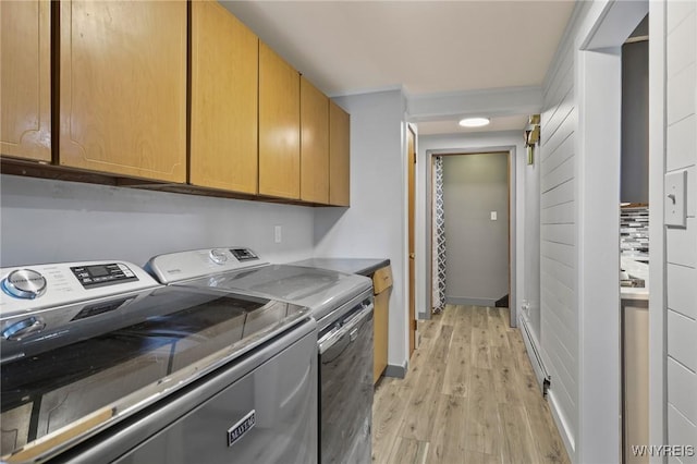 washroom featuring washing machine and clothes dryer, light wood-style flooring, and cabinet space