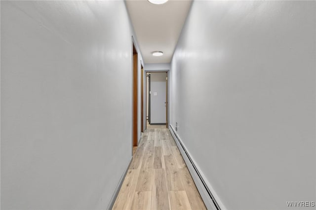 corridor featuring baseboards, baseboard heating, and light wood finished floors