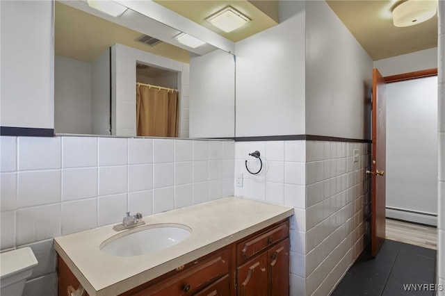 full bath with tile patterned flooring, vanity, toilet, tile walls, and a baseboard heating unit