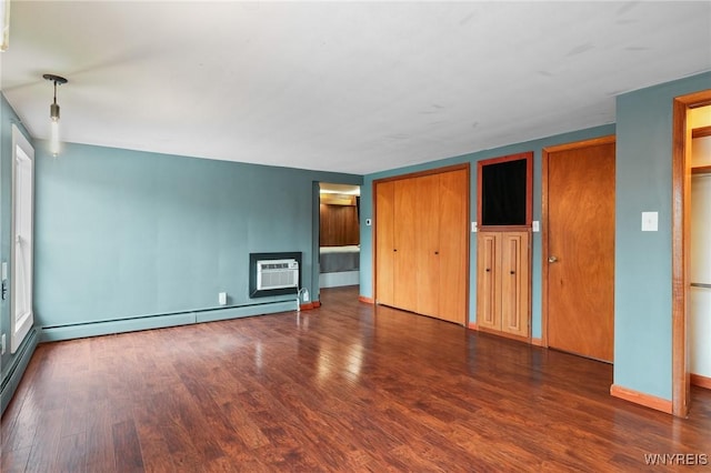 unfurnished living room with an AC wall unit, baseboards, baseboard heating, and wood finished floors