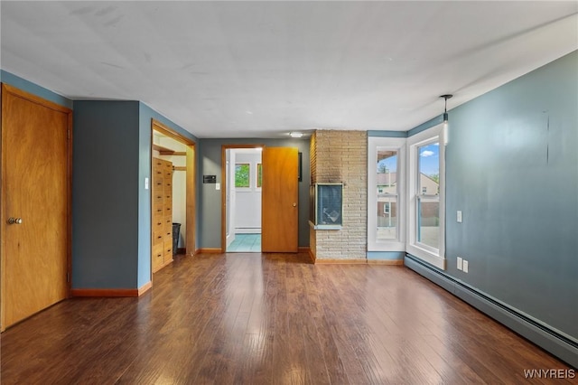 unfurnished living room featuring baseboards, baseboard heating, and wood finished floors