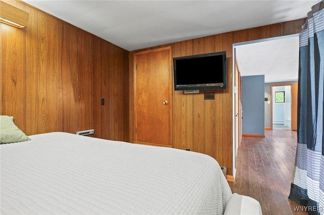 bedroom with baseboards, wood walls, and hardwood / wood-style flooring