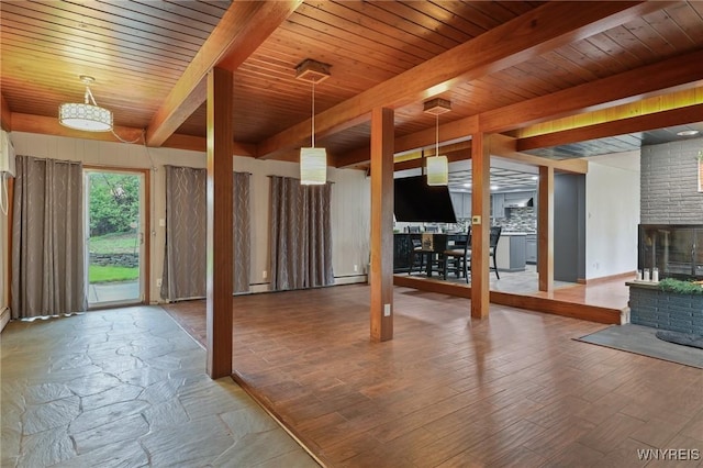 unfurnished living room featuring a brick fireplace, wood finished floors, beam ceiling, a baseboard heating unit, and wooden ceiling
