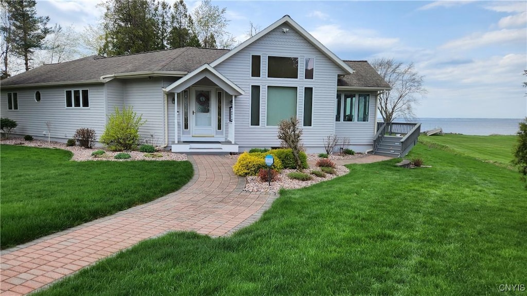 view of front of home featuring a shingled roof, a water view, and a front yard