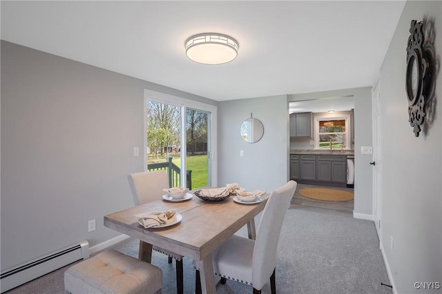 carpeted dining room with a sink, baseboards, and baseboard heating
