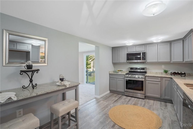 kitchen with gray cabinetry, appliances with stainless steel finishes, and light wood-style floors