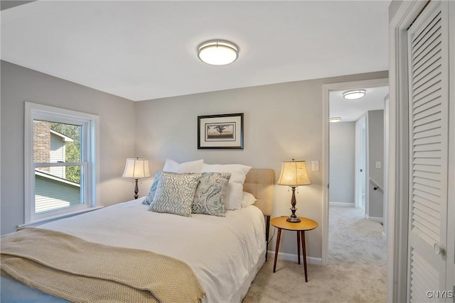 bedroom with baseboards, a closet, and light carpet