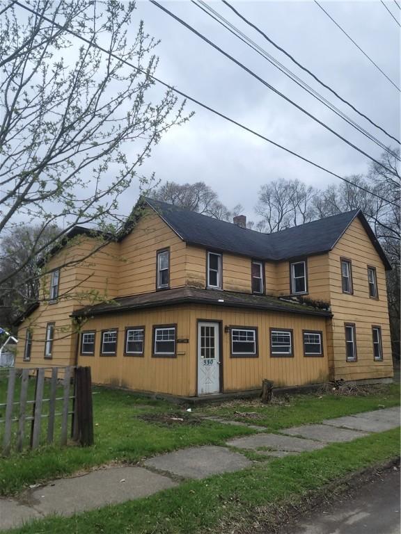 view of side of property with a chimney, board and batten siding, fence, and a lawn