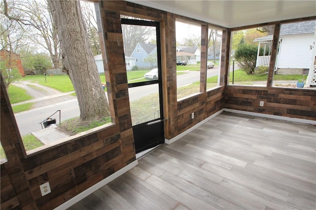 unfurnished sunroom with wood walls and wood finished floors
