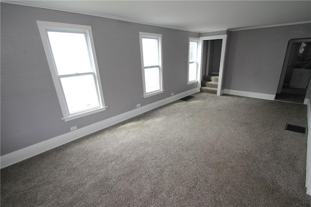 unfurnished living room with baseboards, a healthy amount of sunlight, ornamental molding, and carpet flooring