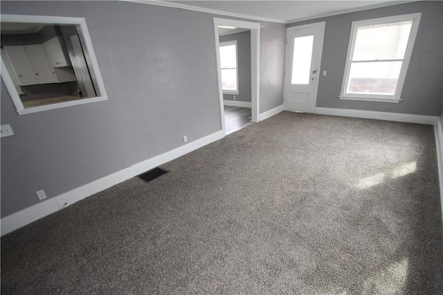carpeted spare room featuring baseboards, crown molding, and visible vents
