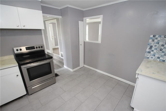 kitchen featuring baseboards, ornamental molding, light countertops, white cabinets, and electric range