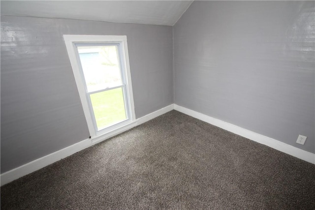 unfurnished room with baseboards and dark carpet