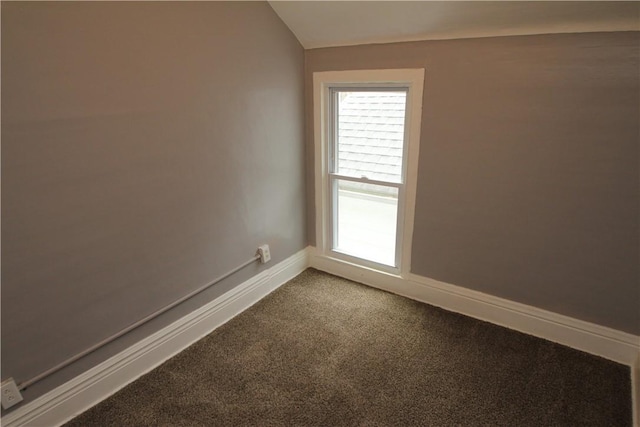 carpeted empty room featuring baseboards and vaulted ceiling